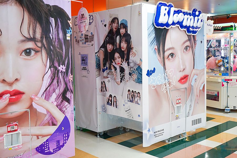 Cabine fotografiche Purikura Bloomit decorate con foto di modelle in una sala giochi.