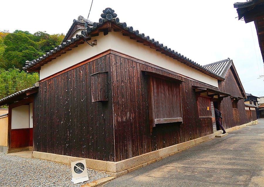 Veduta esterna di una casa tradizionale in legno scuro nel progetto artistico Ishibashi a Naoshima in Giappone.