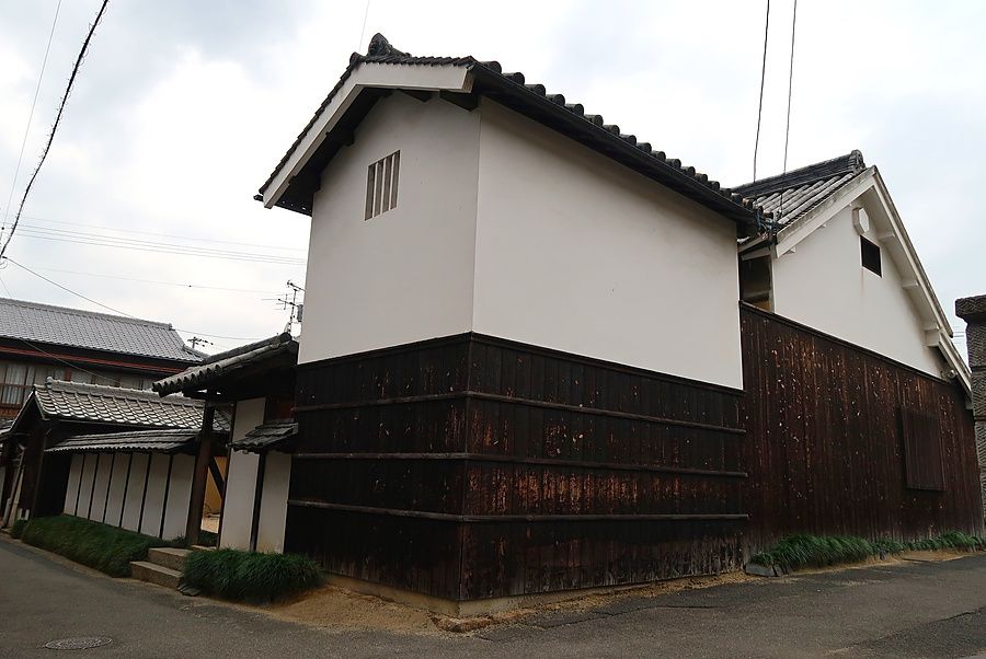 Veduta esterna di una casa tradizionale giapponese con pareti bianche e base in legno scuro a Naoshima.