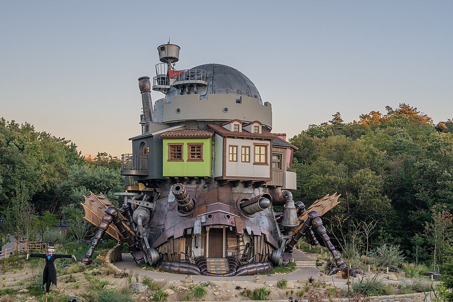 Veduta frontale della grande struttura metallica meccanica del castello errante di Ghibli immersa in un bosco.