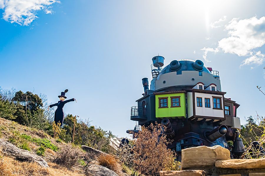 Veduta del castello errante di Howl nel Ghibli Park di Nagoya con una statua a forma di spaventapasseri.