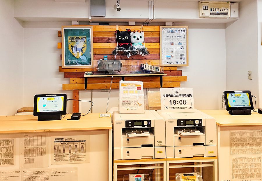 Postazione self-service per spedizioni Yamato Transport a Osaka con stampanti e schermi informativi.
