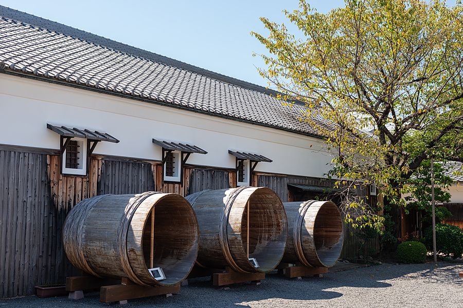 Tre grandi barili di legno vuoti davanti a una tradizionale distilleria di sakè a Fushimi, Kyoto.