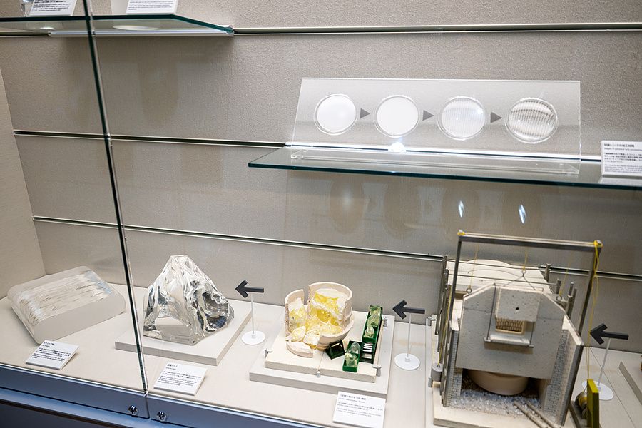 Teca al Nikon Museum di Tokyo con vari campioni di vetro ottico, modelli di forni e schemi esplicativi.