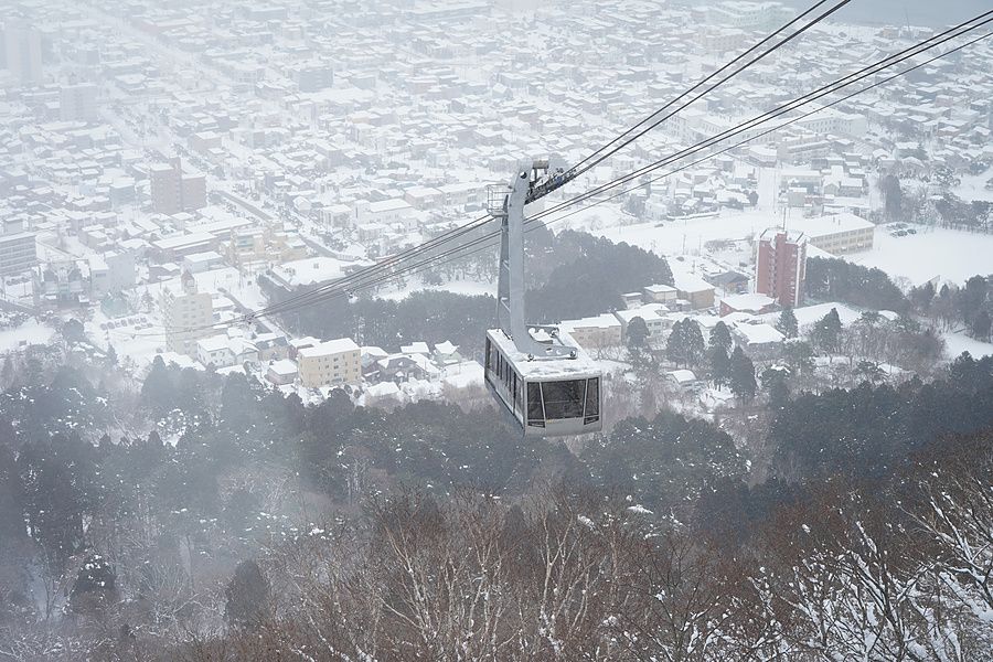 Veduta aerea di una funivia sospesa sopra una città innevata in una giornata di inverno in Giappone.