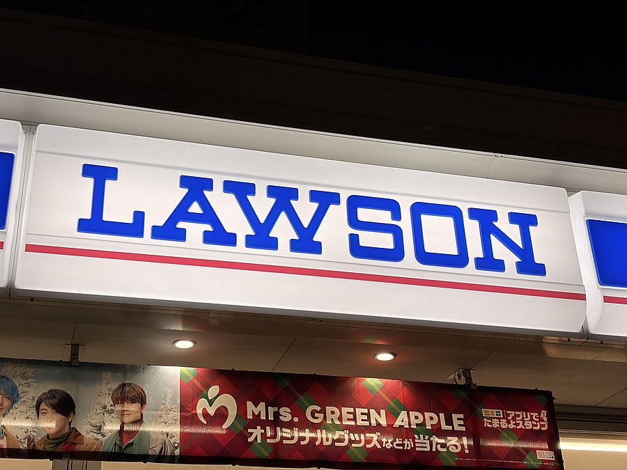 Insegna luminosa del minimarket Lawson con un banner promozionale della band Mrs. GREEN APPLE.