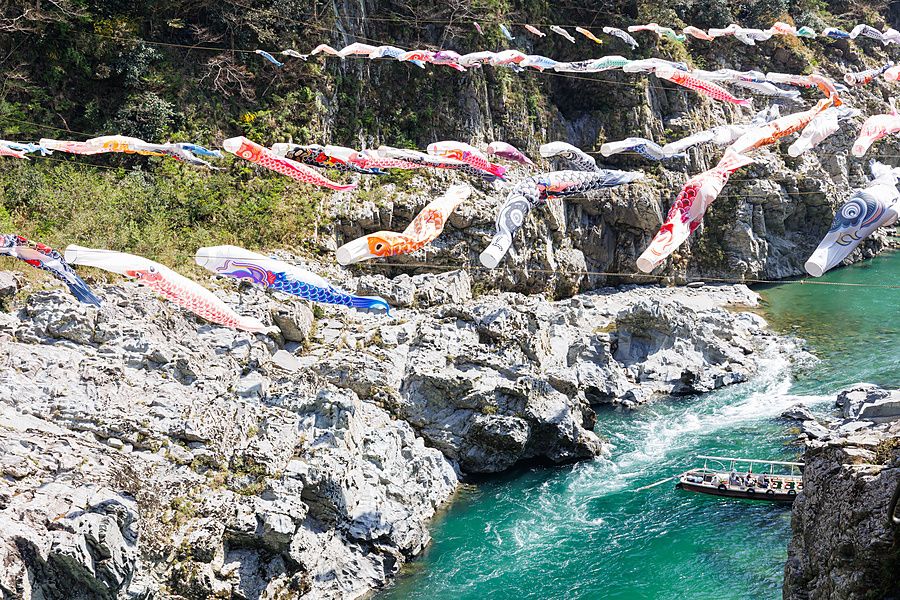 Bandiere a forma di carpa sospese sopra le acque turchesi del fiume Yoshino nella gola di Oboke in Giappone.