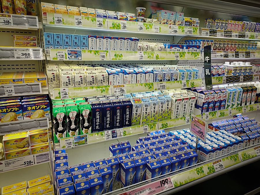 Scaffali di un supermercato giapponese carichi di cartoni di latte in esposizione ordinata.