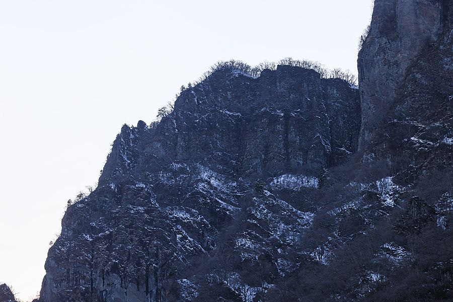 Cresta rocciosa scoscesa del Monte Myogi parzialmente coperta di neve in un paesaggio invernale.
