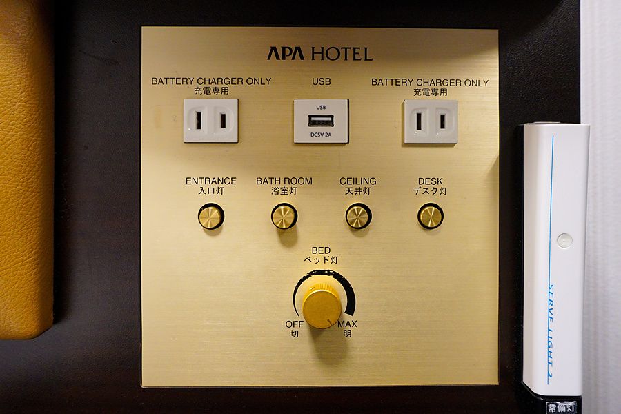 Pannello di controllo dorato con interruttori e prese elettriche installato in una camera d'albergo.