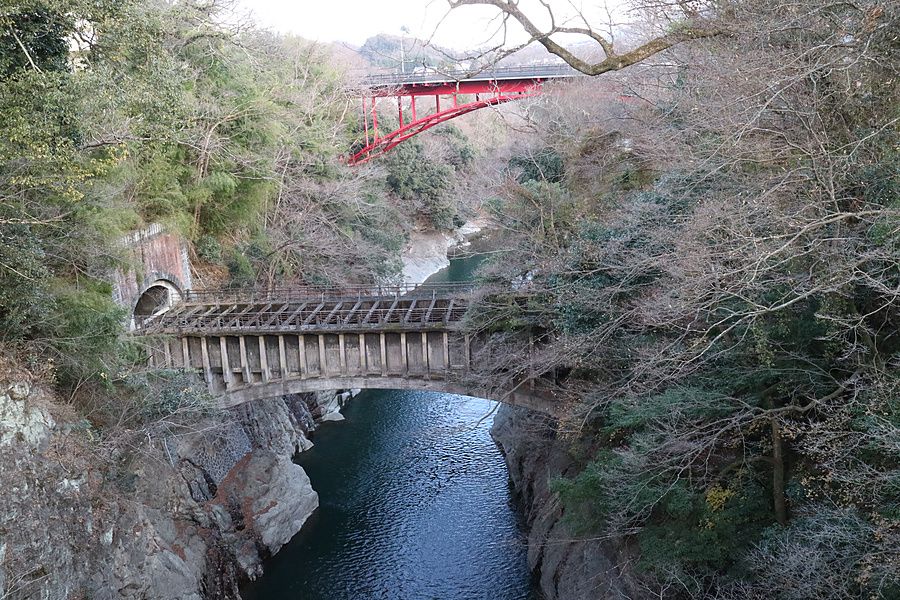 Veduta di un ponte in cemento sopra il fiume Katsura, con un ponte stradale rosso in secondo piano.