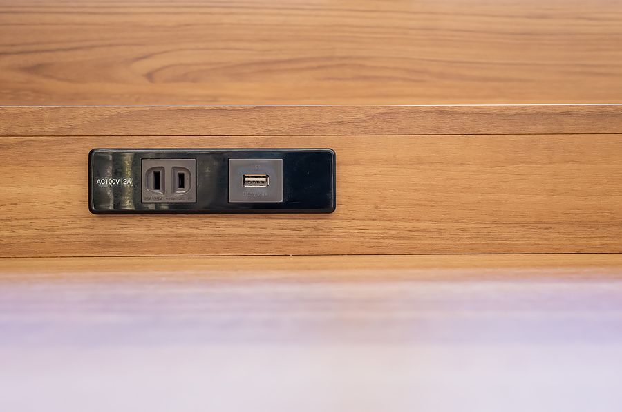 Presa di corrente e porta USB incassate in un piano di lavoro in legno chiaro all'interno di un esercizio commerciale.