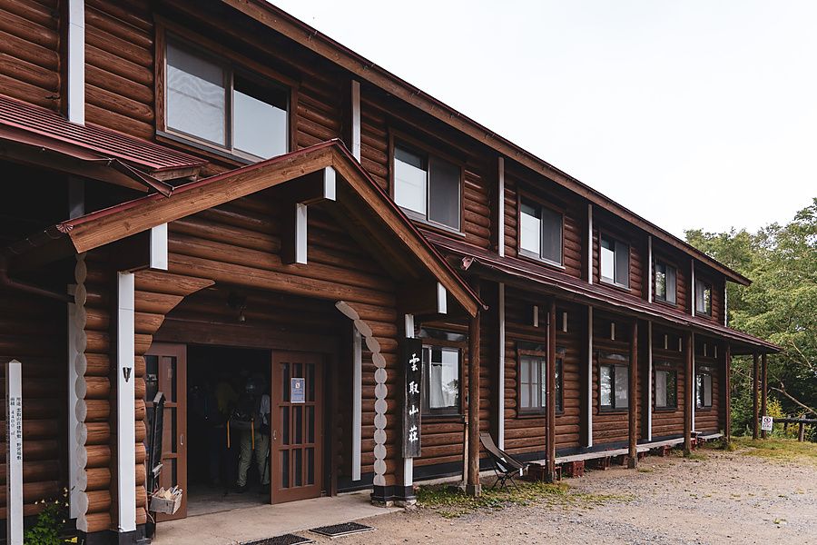 Esterno di un rifugio di montagna in legno a Kumotori, Giappone, con escursionisti che entrano nell'edificio.