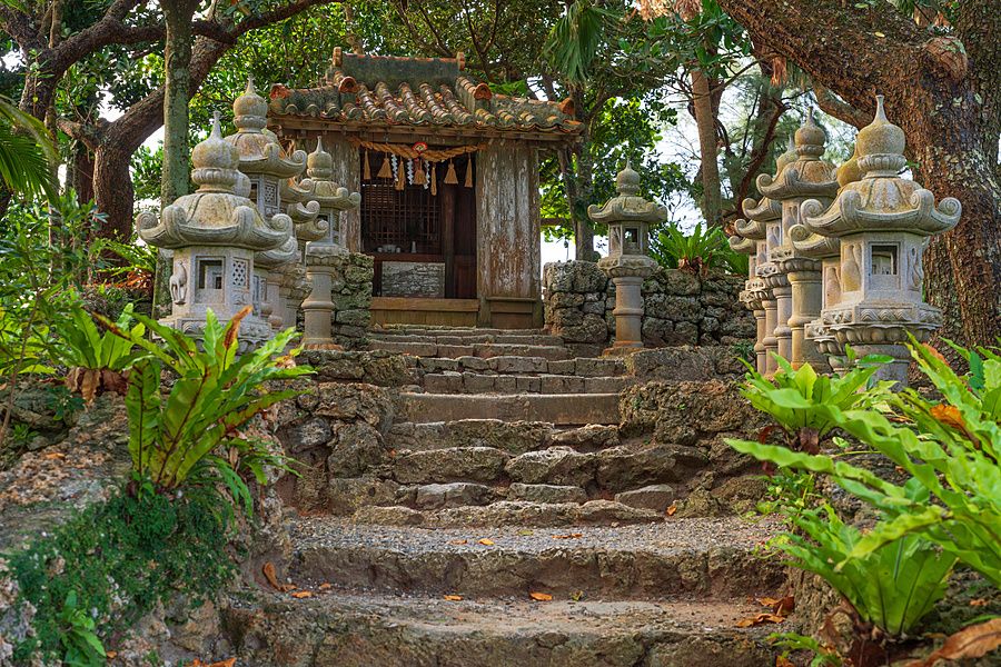 Santuario shintoista a Kabira Bay con scalinata in pietra e lanterne votive circondato da vegetazione tropicale.