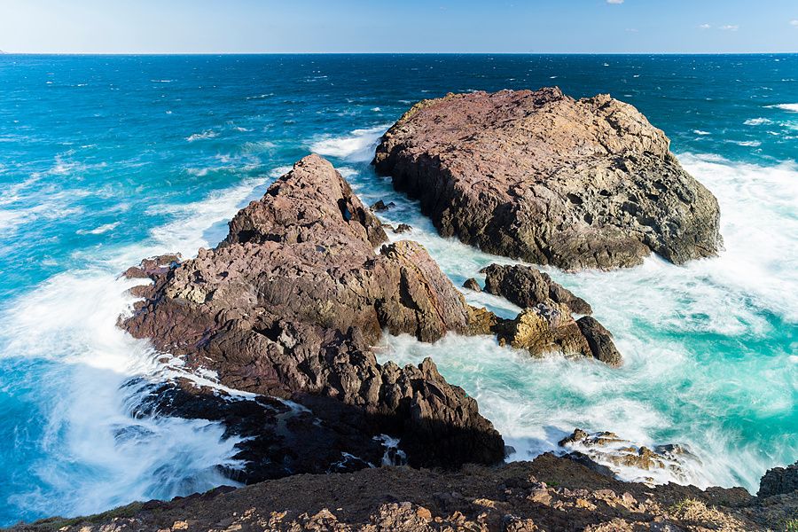 Veduta aerea di scogliere rocciose scure circondate da onde marine turchesi presso il santuario di Motonosumi.
