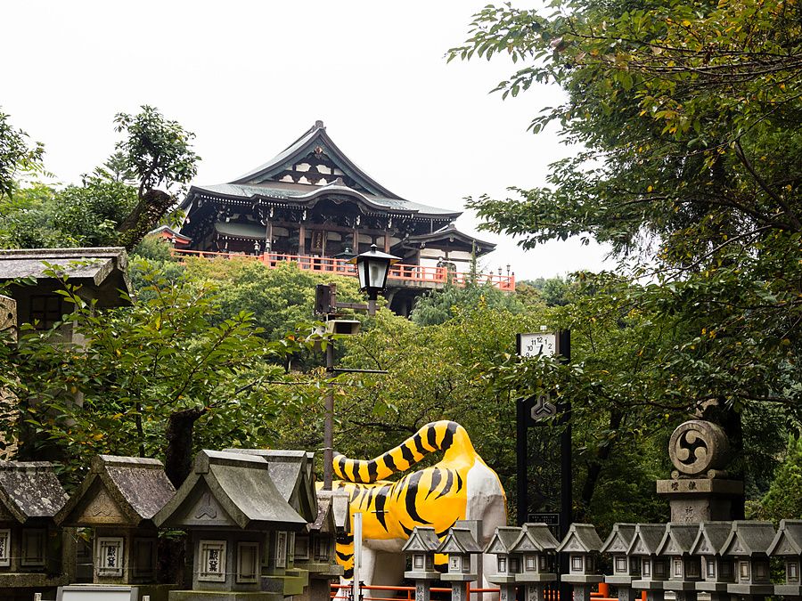 Tempio Chogosonshiji sul monte Shigi a Heguri con una statua di tigre in primo piano e lanterne di pietra.