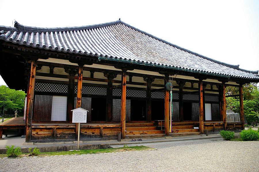 Veduta laterale esterna del tempio Gango-ji a Nara con tetto a falde in tegole e pilastri in legno a vista.