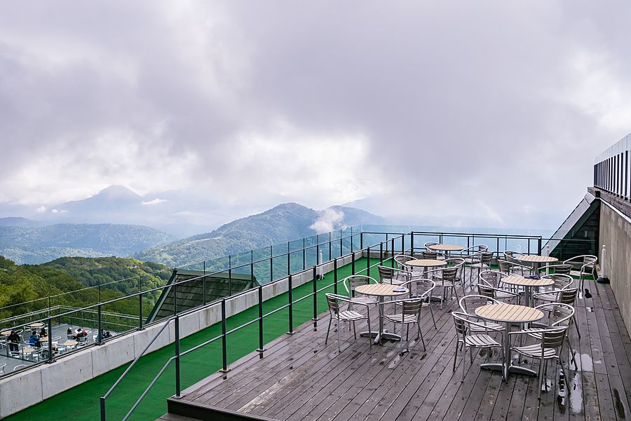 Terrazza panoramica con tavoli e sedie affacciata sulle montagne in una giornata nuvolosa a Tomamu, Hokkaido.