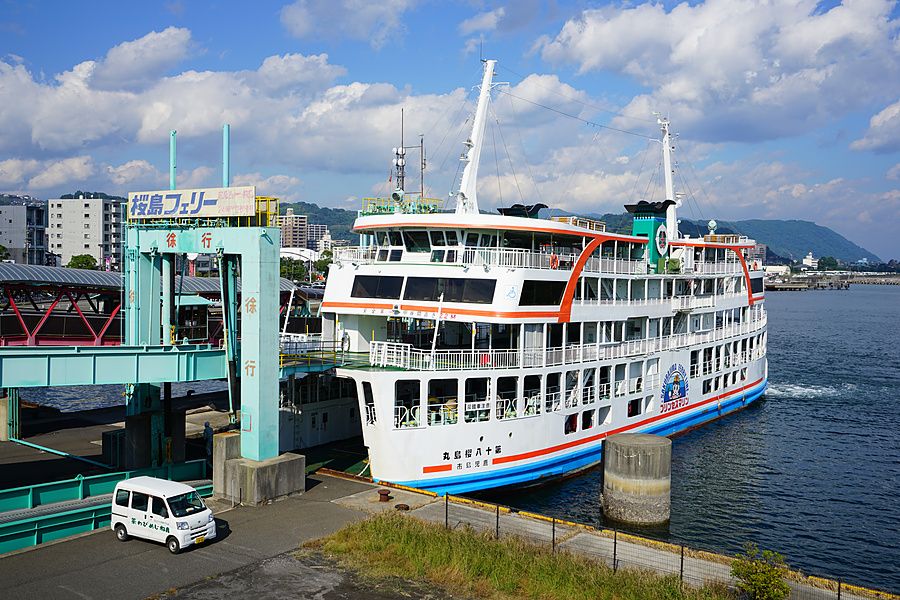 Il traghetto Sakurajima attraccato al molo di Kagoshima con un furgone bianco sulla banchina.