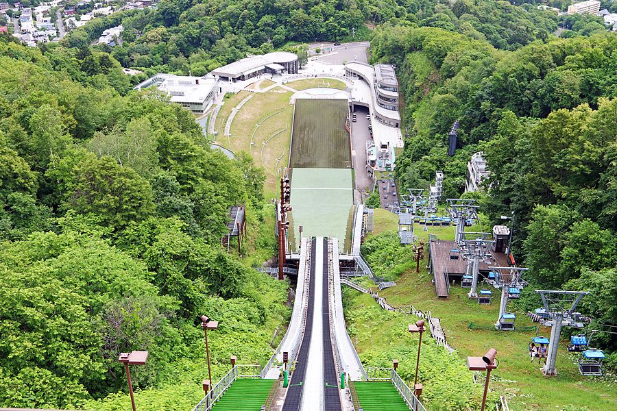 Trampolino olimpico di Okurayama a Sapporo immerso nella foresta verde vista dall'alto.
