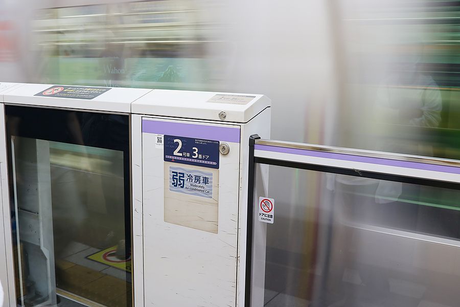 Un treno della metropolitana in arrivo in una stazione di Tokyo visto attraverso le porte di sicurezza della banchina.