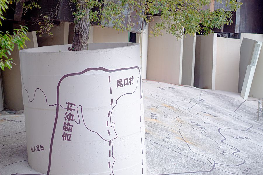 Vaso cilindrico di cemento con disegni di una mappa e un albero in un parco di Yoro, Gifu.