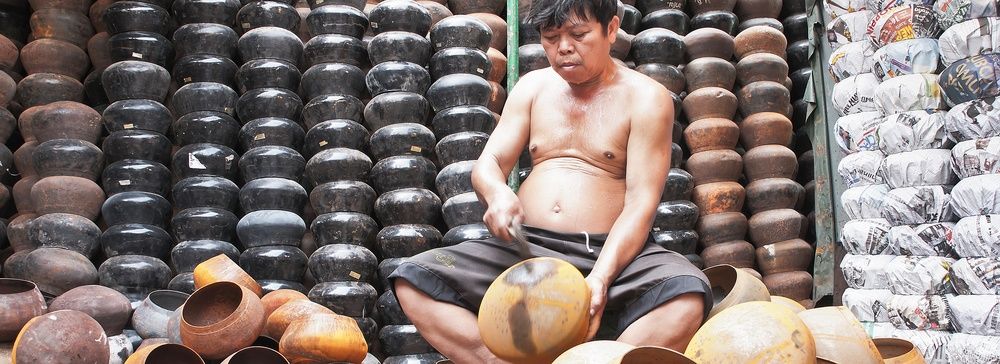 Un uomo lavora con ciotole di metallo nel Villaggio Ban Bat in Thailandia.