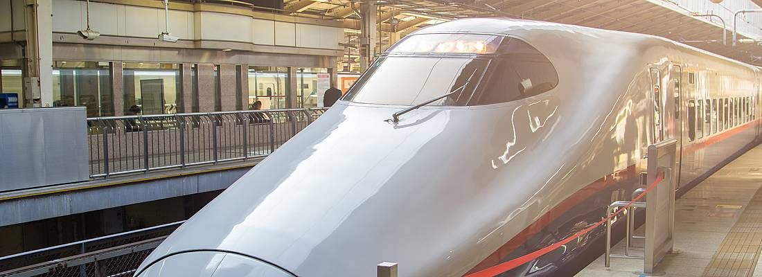 Treno shinkansen fermo in stazione, al tramonto.