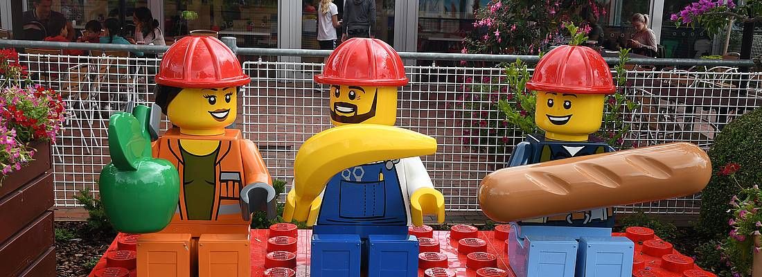 Tre omini lego, vestiti da operai in pausa pranzo.