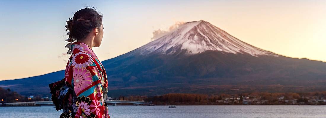 Ragazza asiatica indossa un kimono; sullo sfondo il lago Kawaguchi-ko e il Monte Fuji al tramonto.