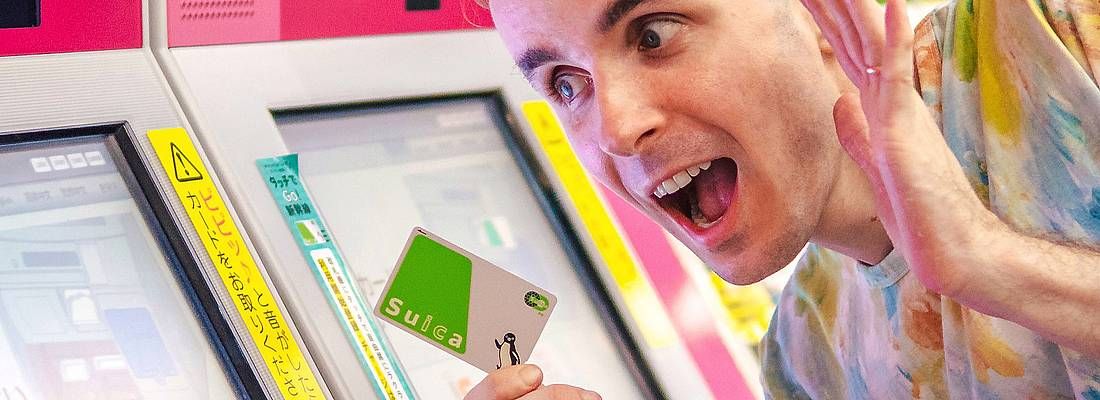 Marco Togni in stazione a Tokyo, con in mano una carta ricaricabile Suica, vicino alle biglietterie automatiche.