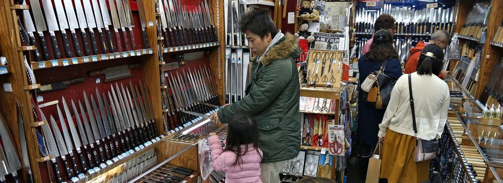 Negozio di coltelli a Tokyo con clienti che osservano i prodotti esposti.