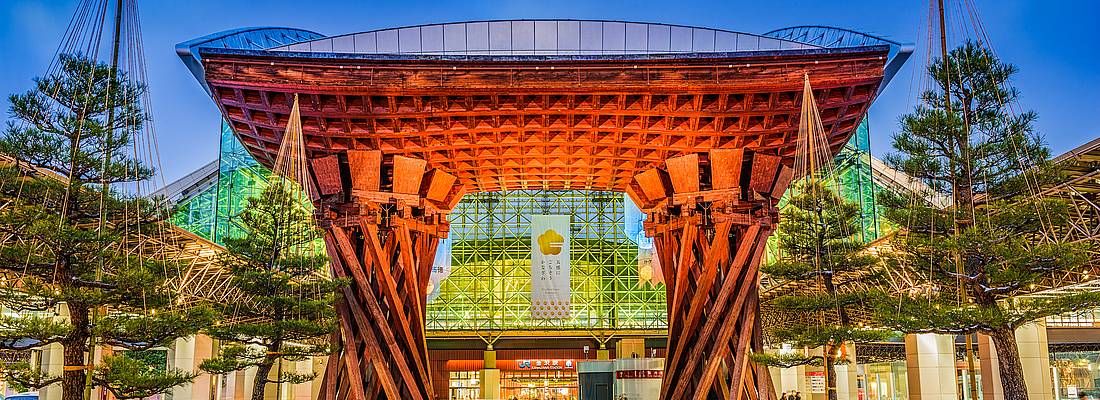 Il grande e moderno torii che segna l'ingresso della stazione di Kanazawa, di sera.