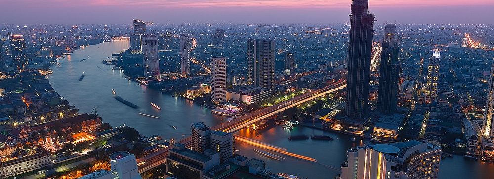 Skyline notturno di Bangkok con grattacieli illuminati e fiume