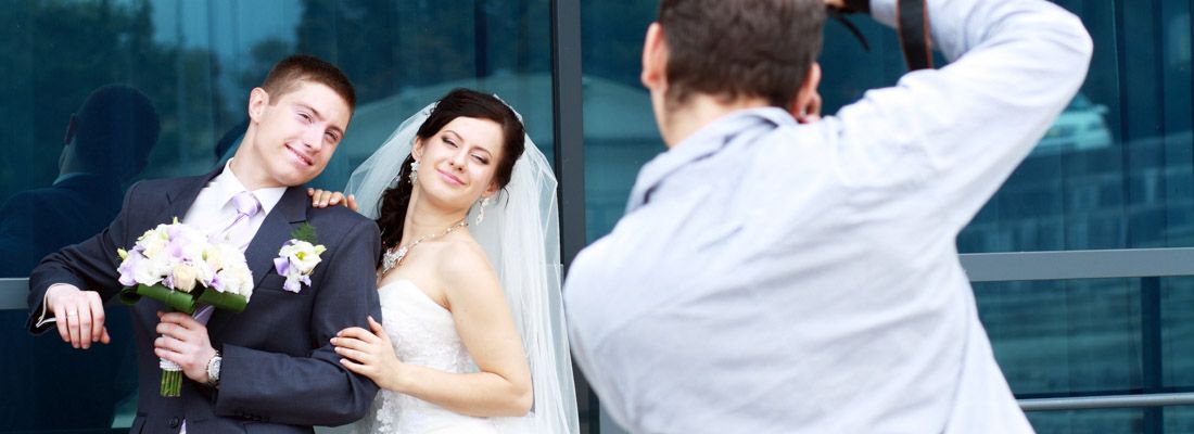 Un fotografo al lavoro mentre fotografa due sposi in posa.