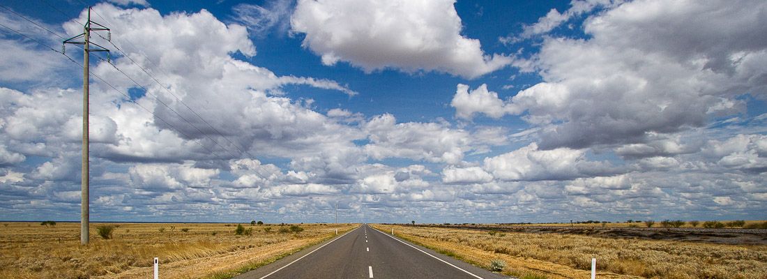 Strada deserta e diritta, con un cielo ricco di splendide nuvole.