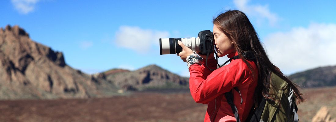 Una ragazza fotografa con un teleobiettivo durante un giro in montagna.