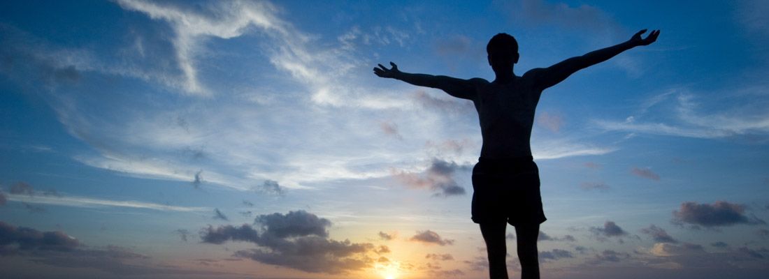 Silhouette di un ragazzo da solo al tramonto, su uno scoglio.