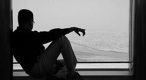 Silhoette di un uomo seduto per terra, mentre ammira la vista di Dubai.