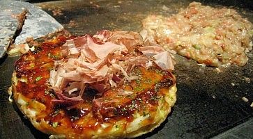 Dettaglio di un okonomiyaki mentre sta cuocendo su una piastra.