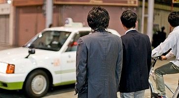 Due salaryman attendono di attraversare la strada.