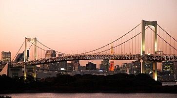 Il Rainbow Bridge di Odaiba al tramonto e sullo sfondo la Tokyo Tower.