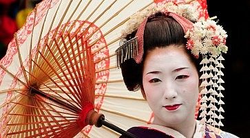 Una geisha con ombrello si mette in posa per una foto ricordo.