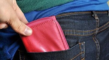 Una mano tenta di rubare un portafoglio, sfilandolo dalla tasca posteriore dei pantaloni.