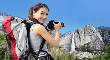 Ragazza fotografa una cascata in un parco naturale.