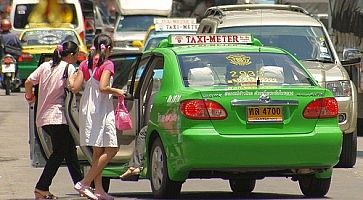 Persone salgono su un taxi verde a Bangkok.