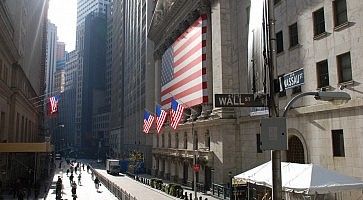 Gioco di ombre e luci a Wall Street, con varie bandiere USA.