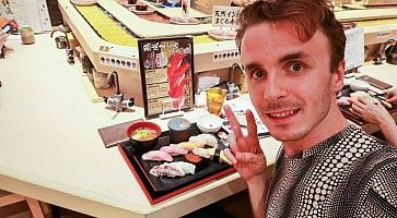 Marco Togni in un ristorante di sushi a Shibuya con piatto di nigiri.