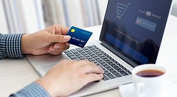 Una persona con una carta di credito in mano sta facendo acquisti online.