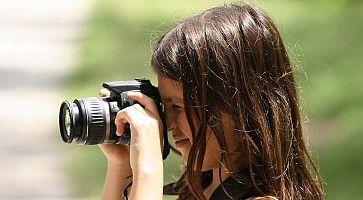 Una bambina fotografa usando una reflex digitale.